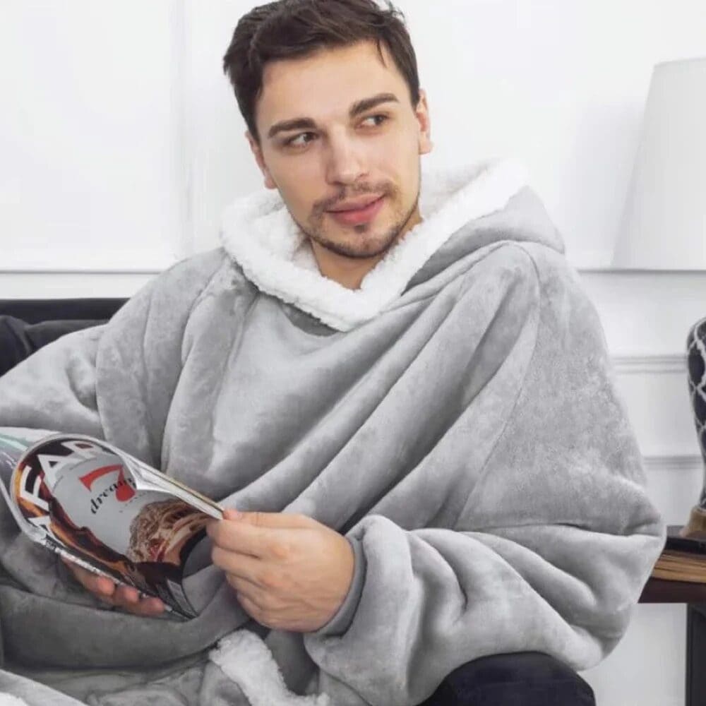 Person in gray blanket hoodie reading.